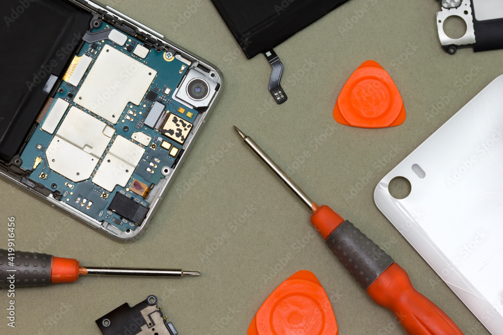 Smartphone and repair tools. Replacing the battery in a modern smartphone. Concept of gadget repair. Smartphone and repair tools. Replacing the battery in a modern smartphone. Concept of gadget repair.