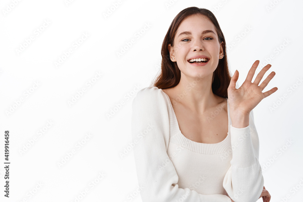 Hi what is up. Portrait of carefree friendly european female entrepreneur, holding hand on chest and smiling broadly while waving raised palm, greeting friend, meeting with mates from work in cafe Hi what is up. Portrait of carefree friendly european female entrepreneur, holding hand on chest and smiling broadly while waving raised palm, greeting friend, meeting with mates from work in cafe