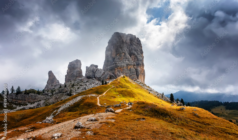 Majestic Cinque Torri in Dolomie Alps during sunset. Stunning view on Five Towers group, overcast sky and foot road. Amazing nature lanscape background. Dramatic sunrise in the mountains.
