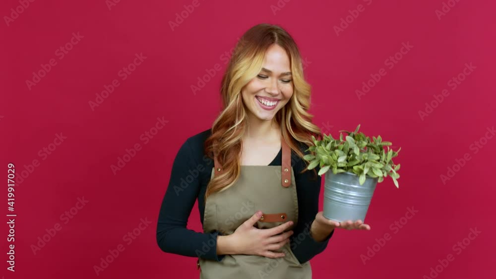 Young blonde girl holding a plant smiling a lot while covering mouth over isolated background Young blonde girl holding a plant smiling a lot while covering mouth over isolated background