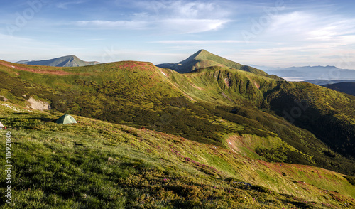 Stunning Alpine Valley at sunny day with majestic mountain peak on background Scenic image of nature at Carpathian mountains with alone hiking tent. resting outdoor concept. Picture of wild area.