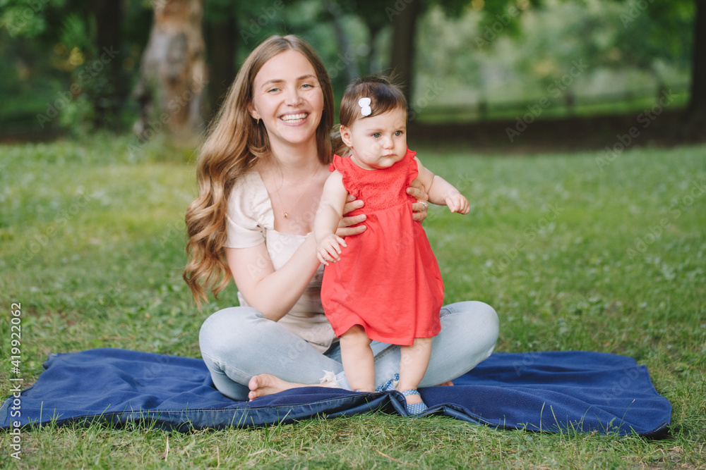 First steps. Young smiling Caucasian mother and girl toddler daughter playing in park. Mom helping child baby to walk independently on her own. Happy authentic family childhood lifestyle. First steps. Young smiling Caucasian mother and girl toddler daughter playing in park. Mom helping child baby to walk independently on her own. Happy authentic family childhood lifestyle.