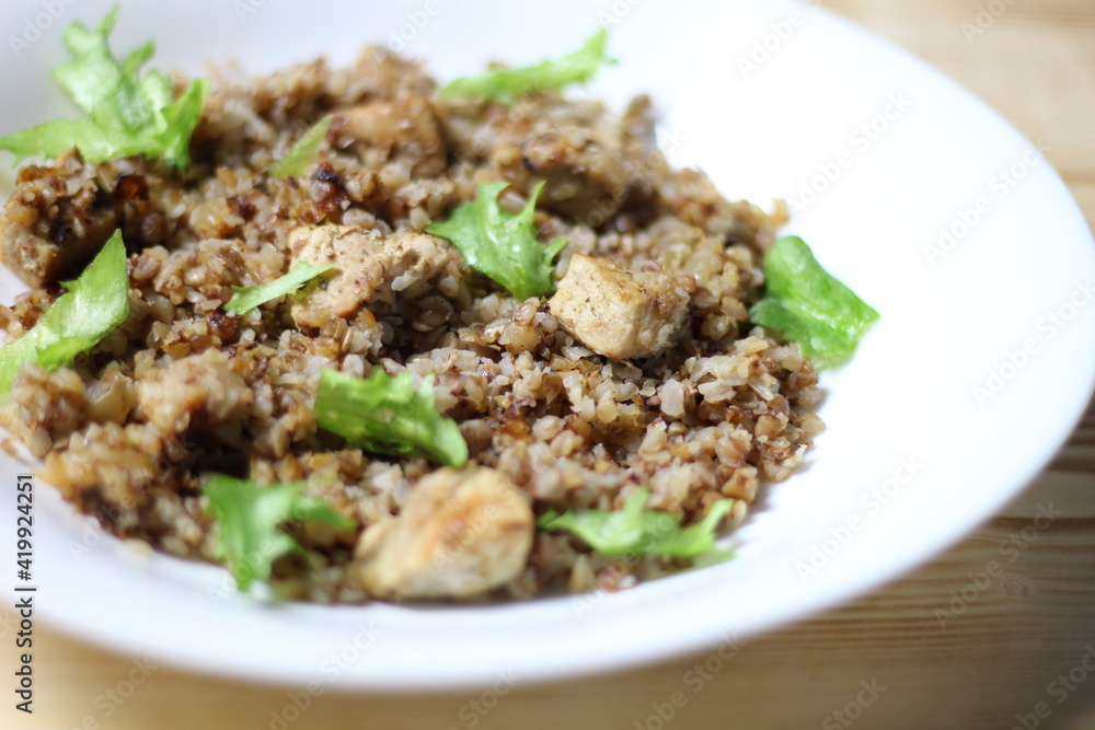 Buckwheat with meat and salad in white plate on wooden background Buckwheat with meat and salad in white plate on wooden background