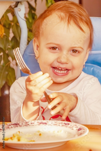 Funny image of little cute child girl with a fork. Happy childhood, food, rest and joy concept.