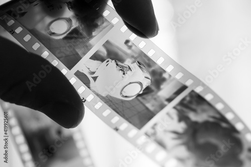 Image of SLR camera on 35mm film in man`s hand with window on background