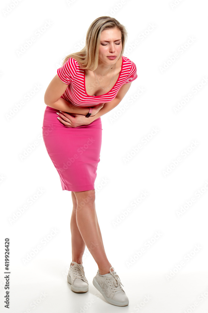 A young woman bent over holds her painful belly with her hands. Isolation on a white background A young woman bent over holds her painful belly with her hands. Isolation on a white background