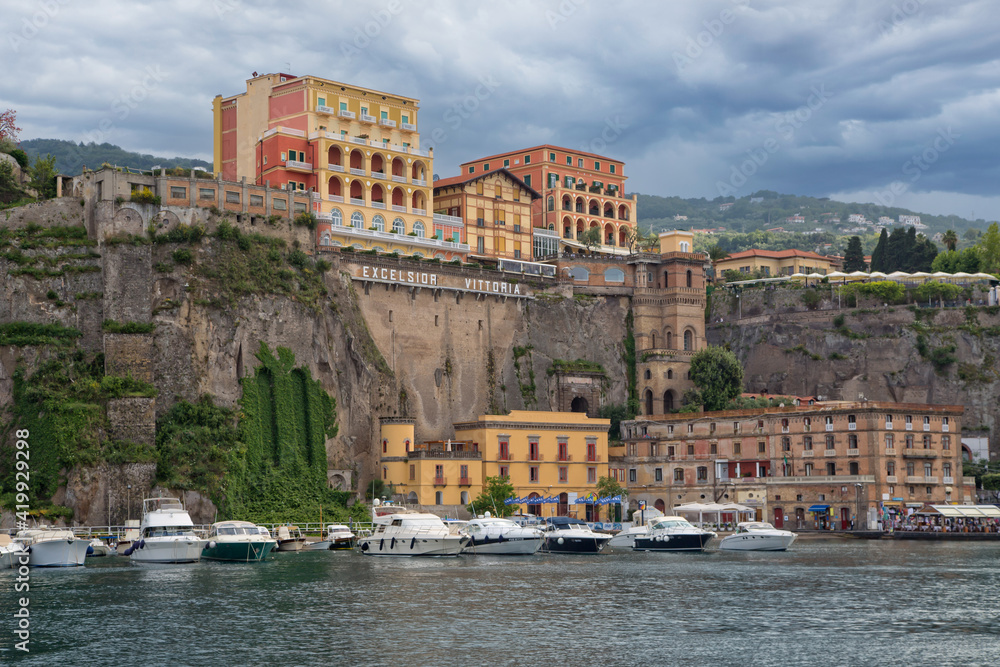 Harbor and cliffs of Sorrento with beautiful old historic buildings.View of boat harbor in Sorrento with colorful buildings and high mountains in the background, Campania, Amalfi Coast, Italy