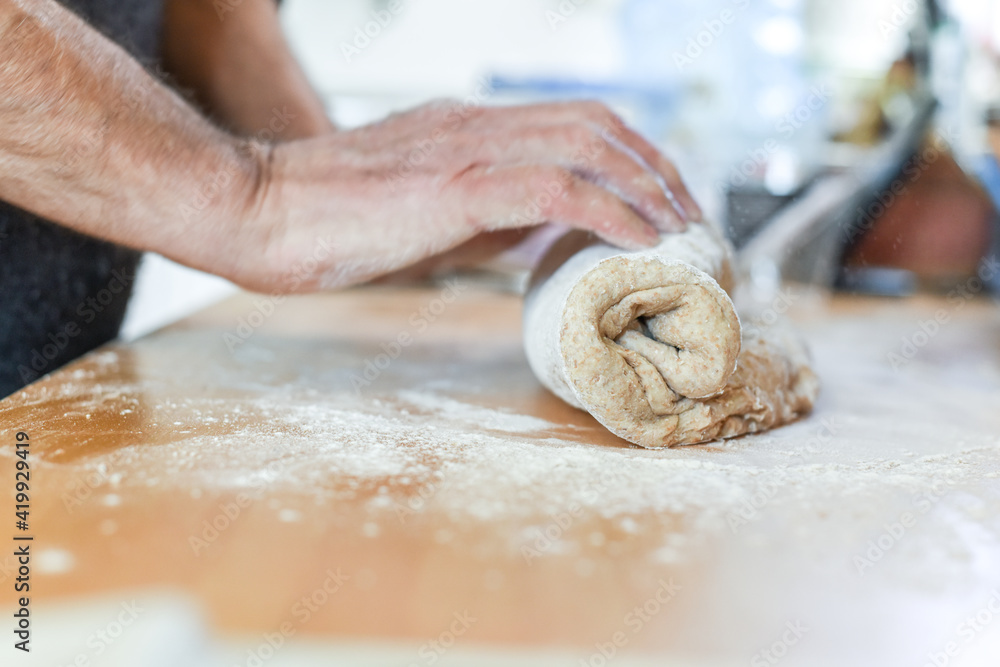 Person making bread in a home kitchen adding ingredients to make the dough and then kneading it by hand Person making bread in a home kitchen adding ingredients to make the dough and then kneading it by hand