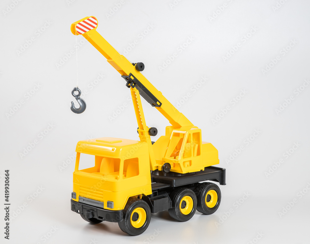 Plastic car. Toy model isolated on a white background. Yellow truck mounted crane.