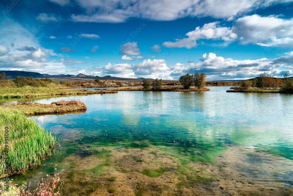 thingvellir National Park turquoise sulfuric vibrant pond clear as glass on a partly cloudy beautiful day