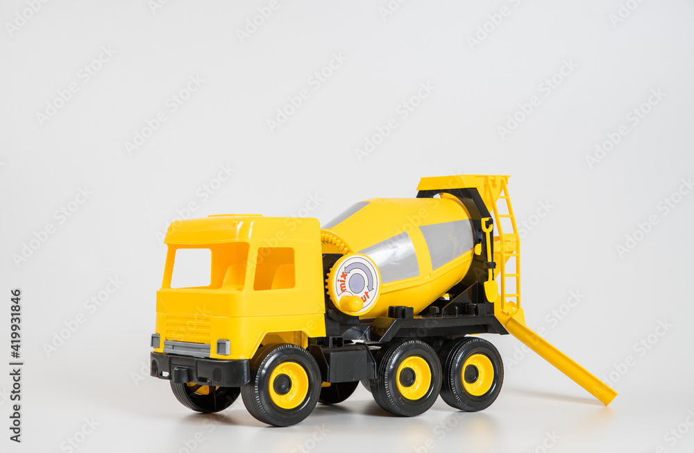 Plastic car. Toy model isolated on a white background. Yellow truck for the transport of building concrete. Plastic car. Toy model isolated on a white background. Yellow truck for the transport of building concrete.