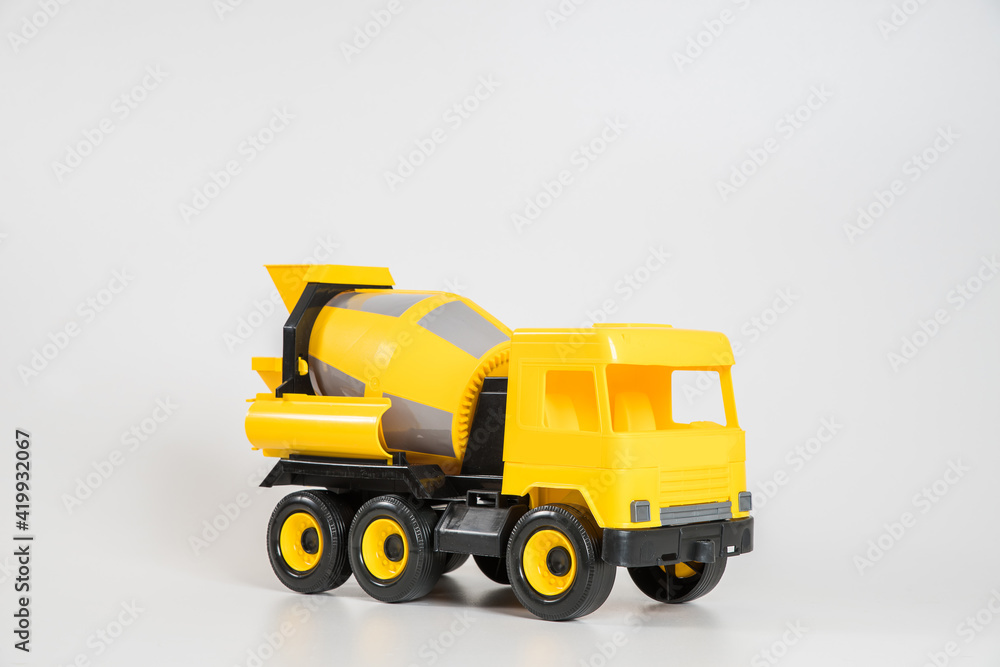 Naklejka premium Plastic car. Toy model isolated on a white background. Yellow truck for the transport of building concrete.