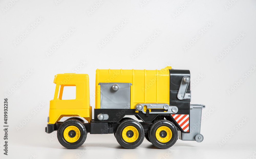 Plastic car. Toy model isolated on a white background. Yellow truck for the transport of garbage.
