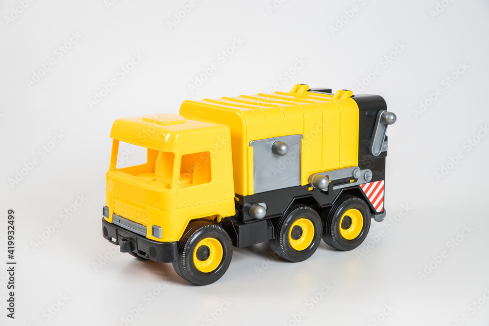 Plastic car. Toy model isolated on a white background. Yellow truck for the transport of garbage.