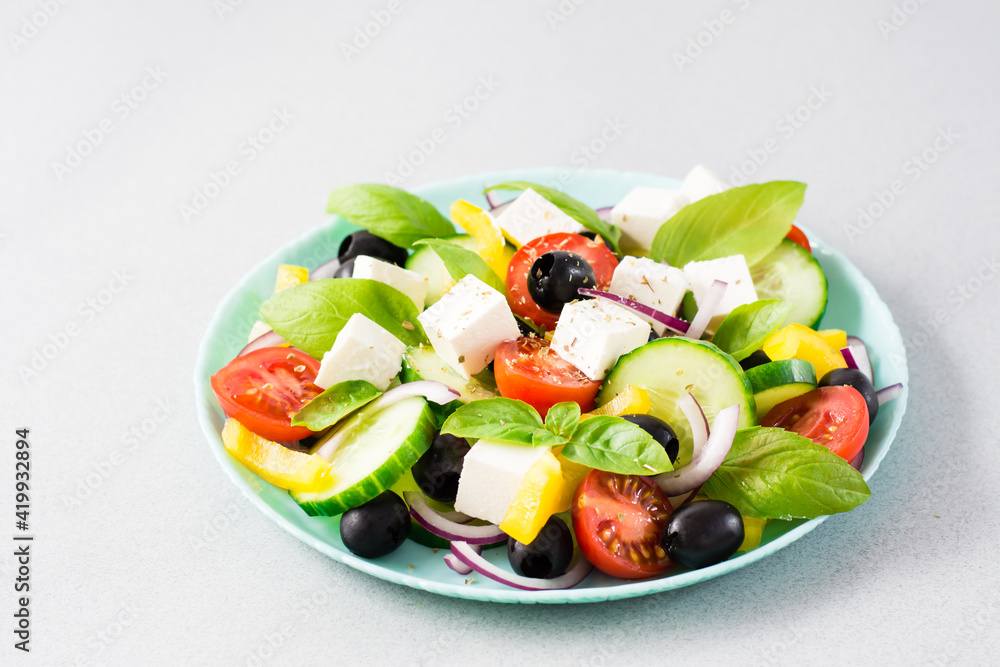 Fresh homemade greek salad with basil leaves on a plate on the table. Domestic life Fresh homemade greek salad with basil leaves on a plate on the table. Domestic life