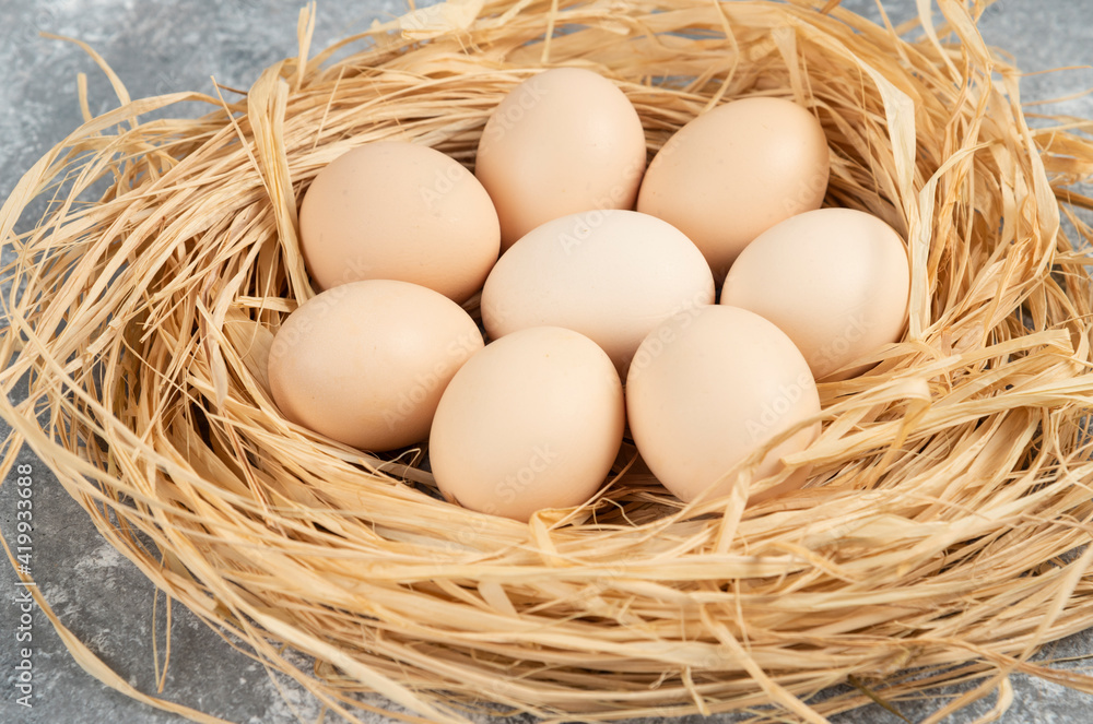 Bunch of raw eggs with bird nest on marble surface Bunch of raw eggs with bird nest on marble surface