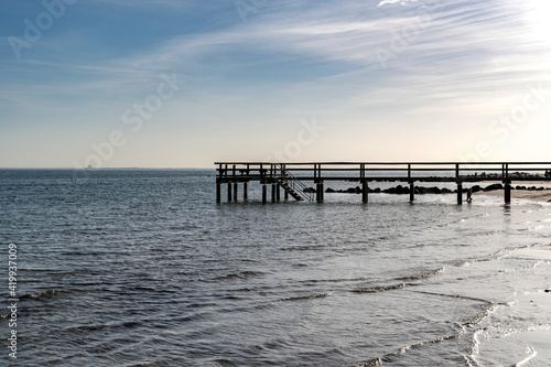 a ridge of stones go into the baltic sea on a sandy beach and pier