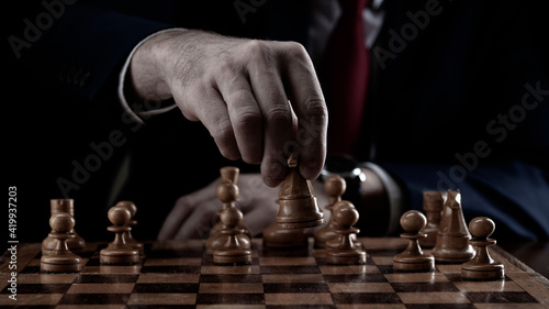 Strategy and business planning concept. A businessman at a chessboard in front of lined up white and black pawns. Strategy and tactics, battle readiness, battle start