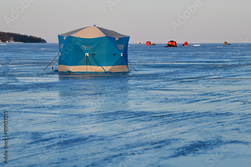 Blue ice fishing tent on frozen Kempenfelt Bay of Lake Simcoe in winter at sunset
