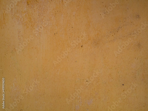 A background of yellow oil paint, cracked with age, on an aluminum sheet. The texture of a peeling metal wall or door of a garage, production room, or factory.