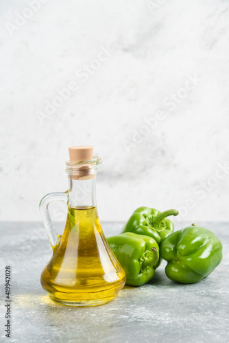 Green chili peppers with a bottle of extra virgin olive oil on marble background