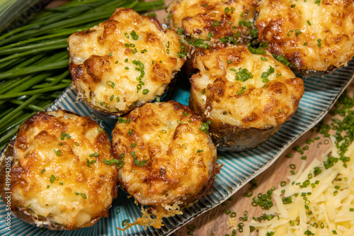 A selection of delicious Fish Pie Potato Skins topped with cheese and garnish on a wooden kitchen table background