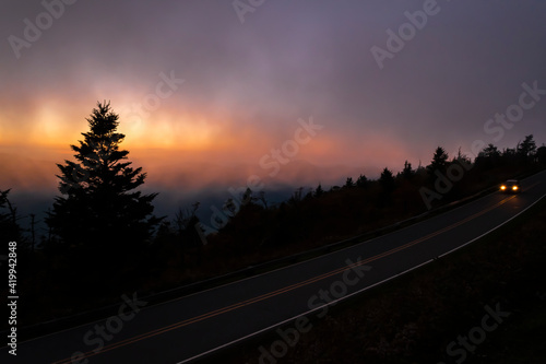 Fotografie A lonely road, a fogy night just after sunset orange yellow and red-light orange