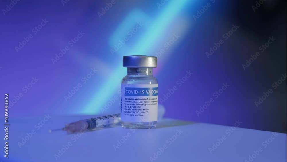 Glass ampoule with COVID-19 VACCINE label. Neon looped animated background Glass ampoule with COVID-19 VACCINE label. Neon looped animated background