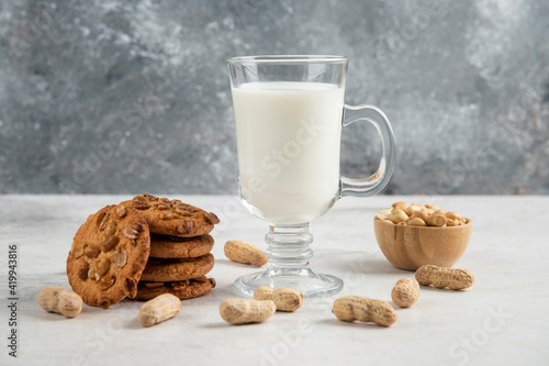 Glass of fresh milk and tasty biscuits with peanuts on marble background