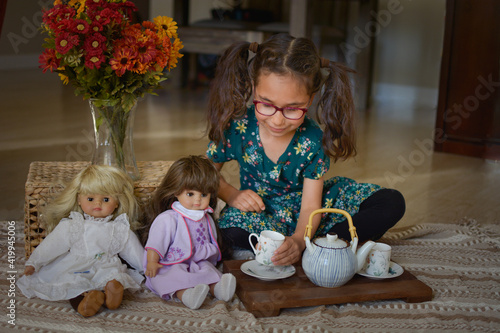 Valokuva Girl playing with dolls tea party at home on the floor