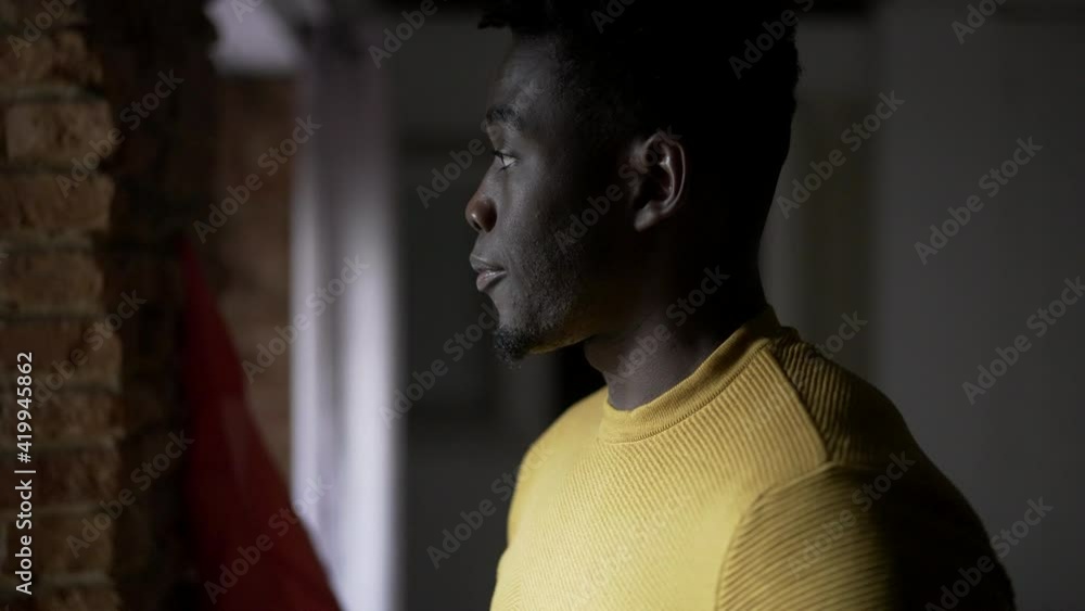 African man standing by window thinking about life. Concerned worried emotion African man standing by window thinking about life. Concerned worried emotion