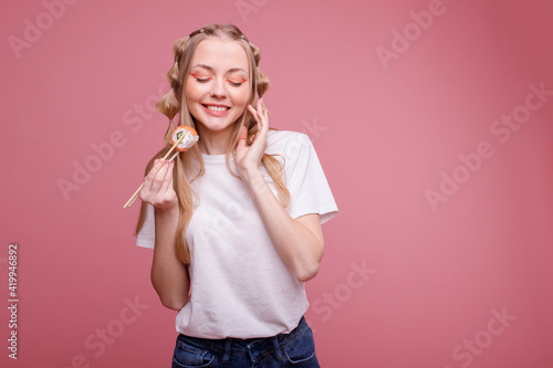Attractive girl with roll Philadelphia smiles on pink background