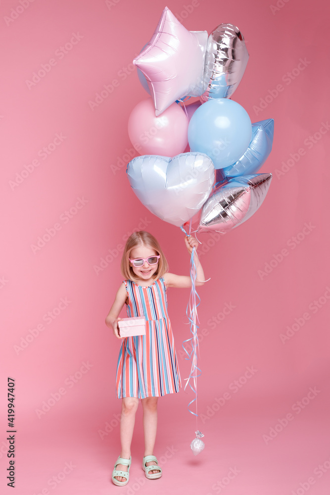 girl in glasses with a gift and balloons on a pink background