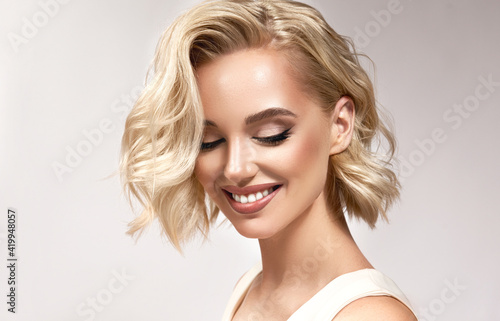 Beautiful model girl with short hair .Beauty woman with blonde  curly hair.  Hair dye .Fashion, cosmetics and makeup photo
