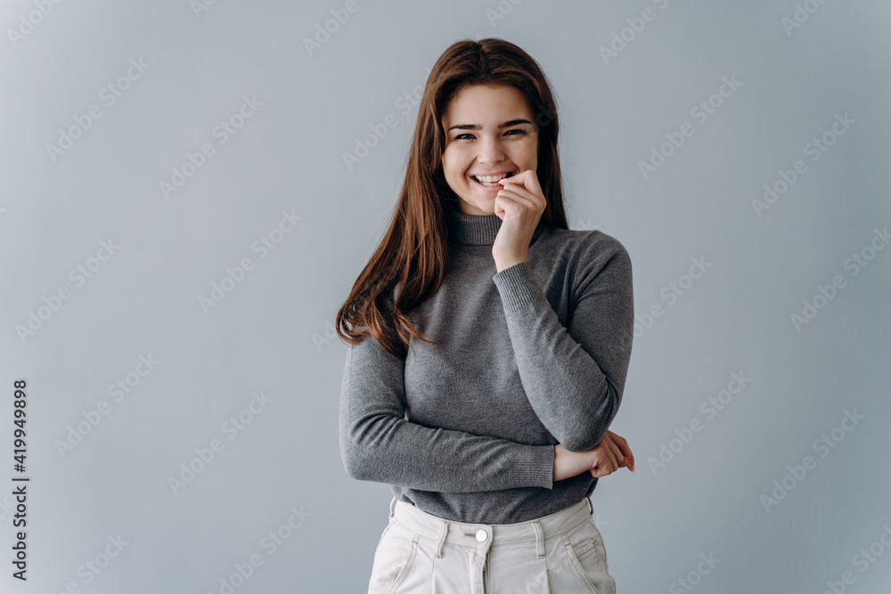Beautiful, cute young girl smiling on a gray background. Isolated brunette, place for text, copy space. Beautiful, cute young girl smiling on a gray background. Isolated brunette, place for text, copy space.