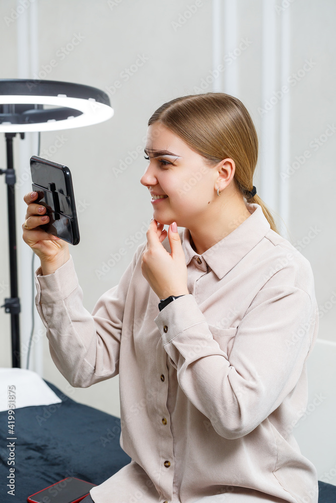 Makeup artist applies eyebrow tint for the permanent makeup of a young girl. Professional make-up and cosmetic face care Makeup artist applies eyebrow tint for the permanent makeup of a young girl. Professional make-up and cosmetic face care