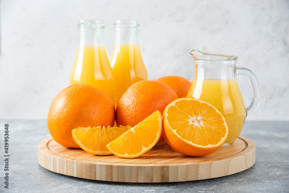 A wooden board full of juicy slices of orange fruit on stone background A wooden board full of juicy slices of orange fruit on stone background
