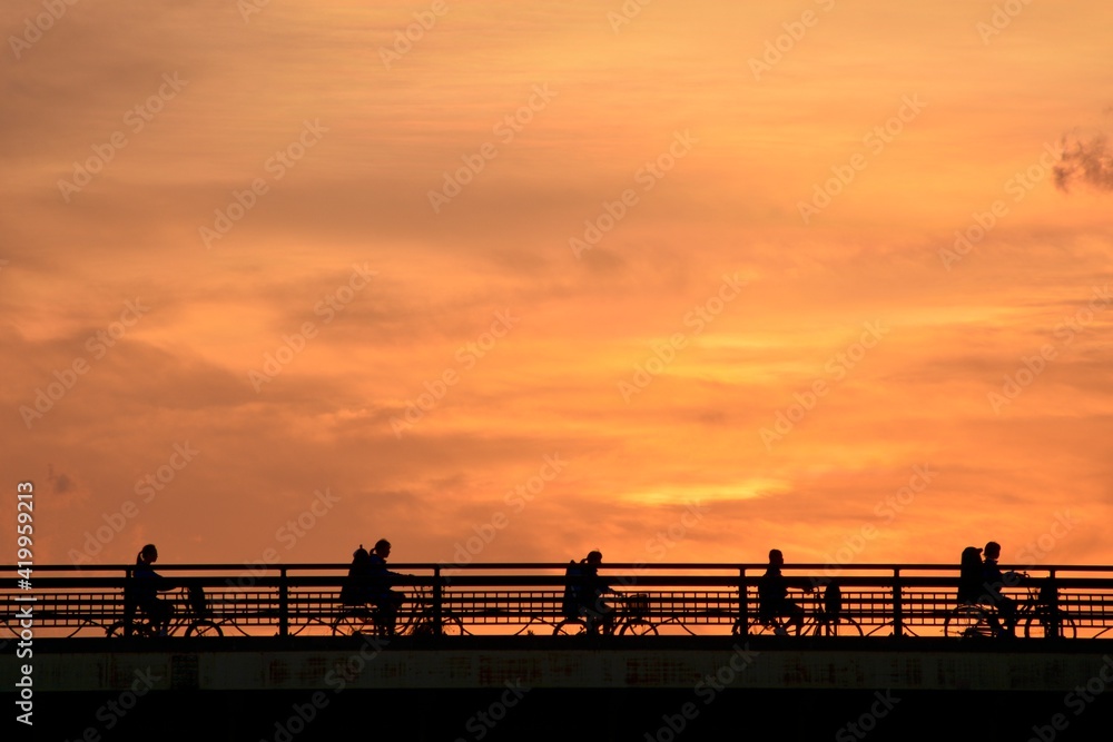 bicycle crossing the bridge.   “Golden hour” dim light sky.  blurred focus silhouette image. Japan・tokyo. 