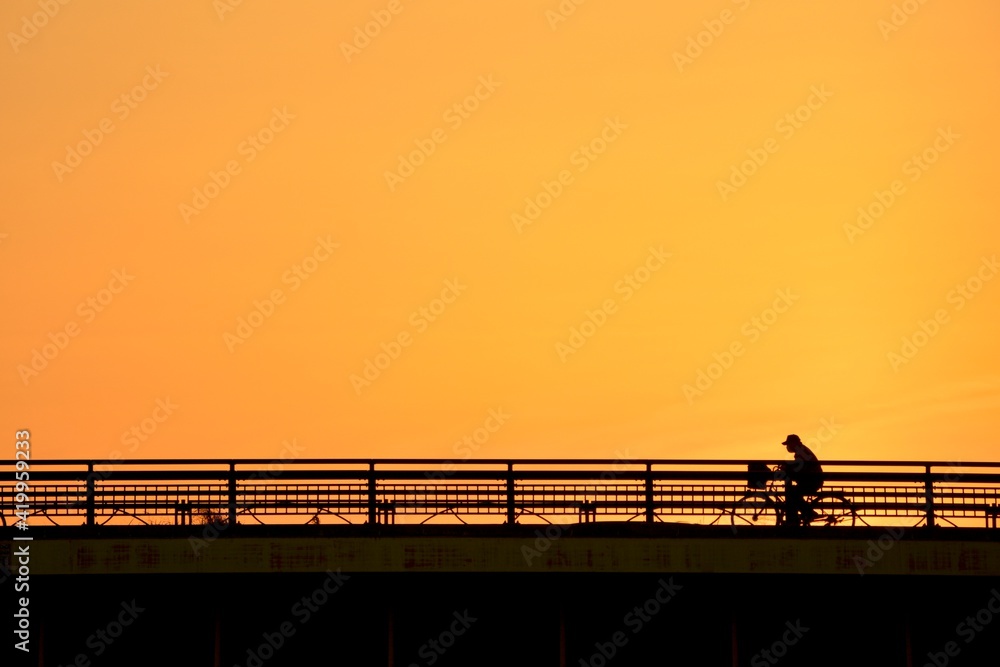 bicycle crossing the bridge.   “Golden hour” dim light sky.  blurred focus silhouette image. Japan・tokyo. 
