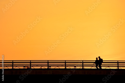 People crossing the bridge.“Golden hour” dim light sky. blurred focus silhouette image. Japan・tokyo. 