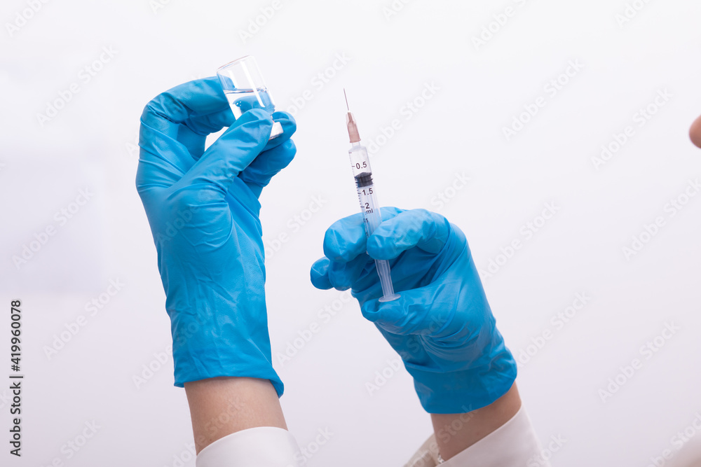 Doctor scientis in protective gloves holding glass vial with injection liquid. Vaccination against influenza and coronavirus Doctor scientis in protective gloves holding glass vial with injection liquid. Vaccination against influenza and coronavirus