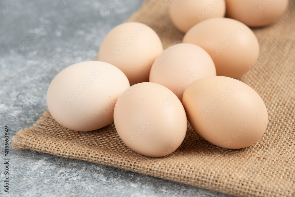 Pile of organic uncooked eggs with tablecloth on marble surface Pile of organic uncooked eggs with tablecloth on marble surface