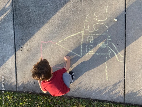 child at sunset playing in a park in Orlando Florida community park drawing a house with chalk in sidewalk 