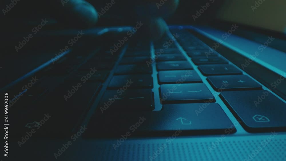 A male hands typing on an illuminated laptop keyboard in slow motion. A male hands typing on an illuminated laptop keyboard in slow motion.