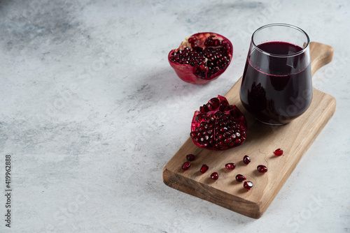 A glass cup of pomegranate juice on a wooden board