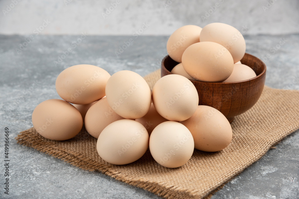 Wooden bowl of organic raw eggs on marble surface Wooden bowl of organic raw eggs on marble surface