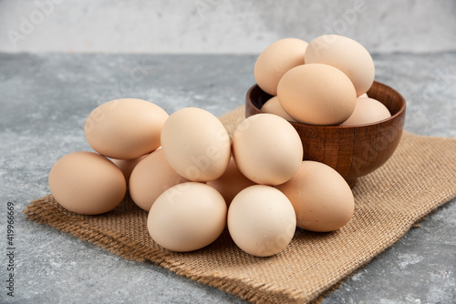 Wooden bowl of organic raw eggs on marble surface