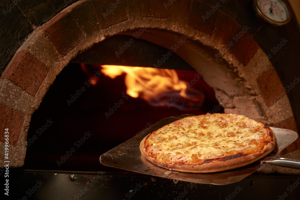 pizza saliendo del horno con llamas