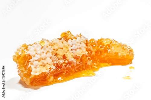 a piece of honeycomb lies on a white background with honey close up