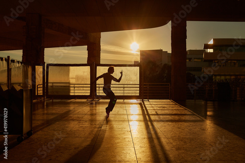 A young man makes a Michael Jackson pose in the backlight. He stands on his tiptoes. Hihee!